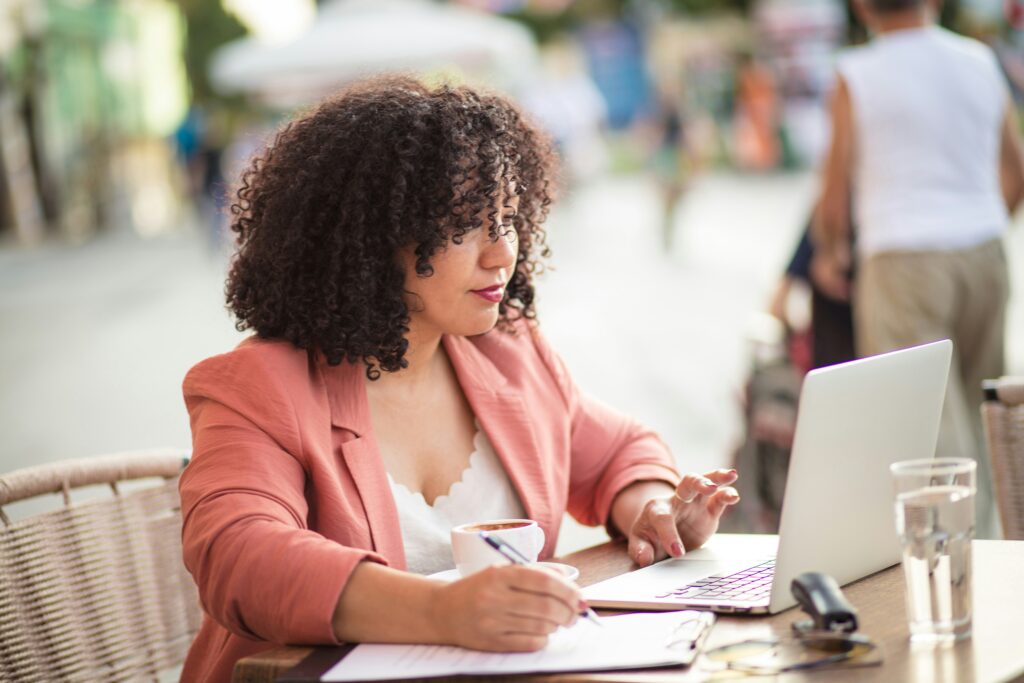 African-american woman takings notes at desk with laptop