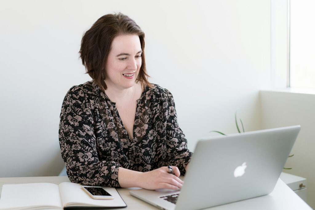 Angelica Hesse smiling while working on laptop